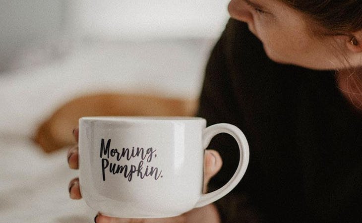 image of woman drinking coffee in bed - daylight saving time