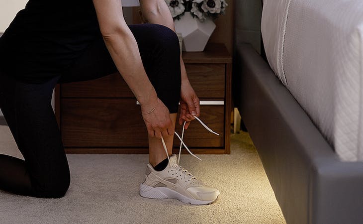 saatva mattress in runner's world - image of woman lacing up sneakers next to bed