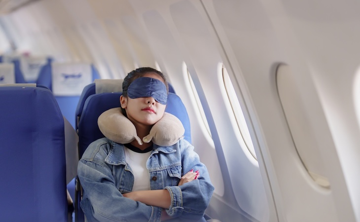Person sleeping on airplane seat.