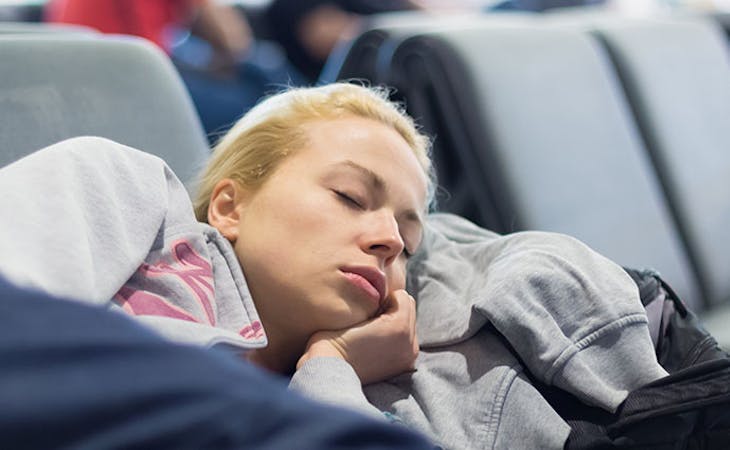 image of woman sleeping in airport while traveling