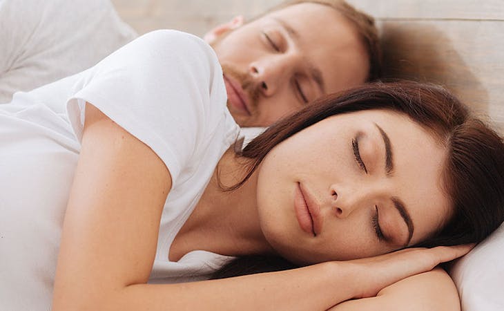 image of couple sleeping in bed - how to break in a memory foam mattress