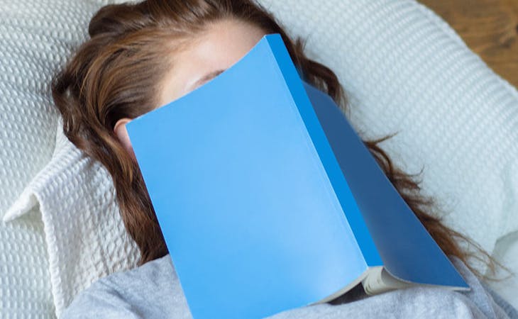 image of woman with book over her face - sleep learning