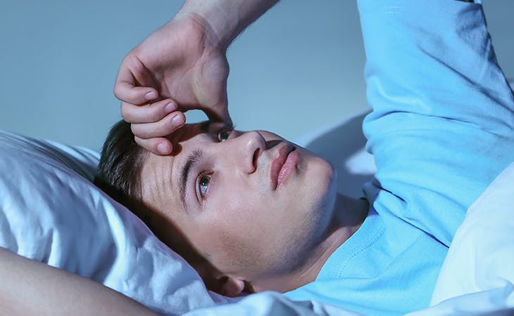 image of man with anxiety awake in bed