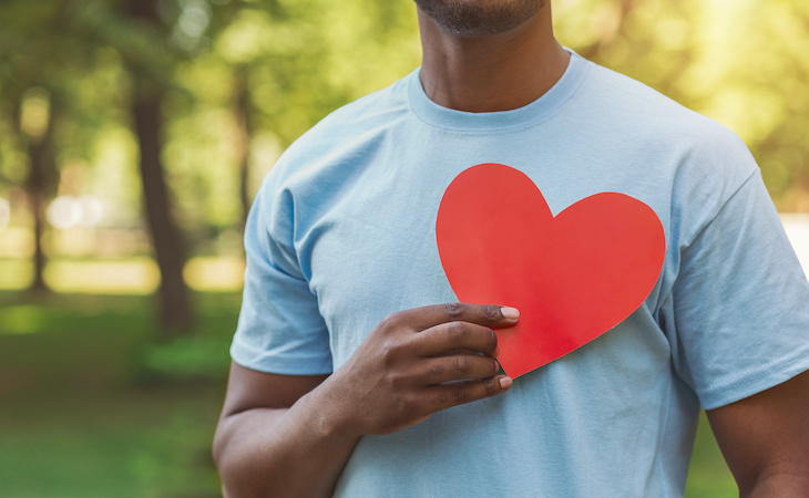 Person holding red heart on his chest