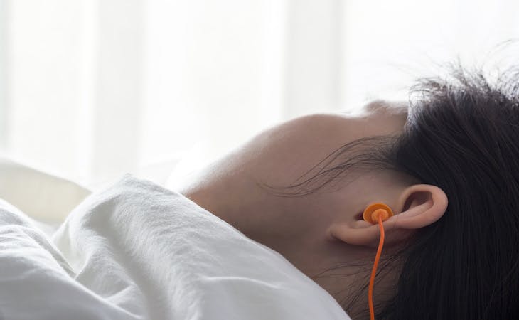 how to sleep through noise - image of person sleeping with earplugs