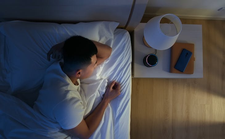 person looking at smart home device from bed
