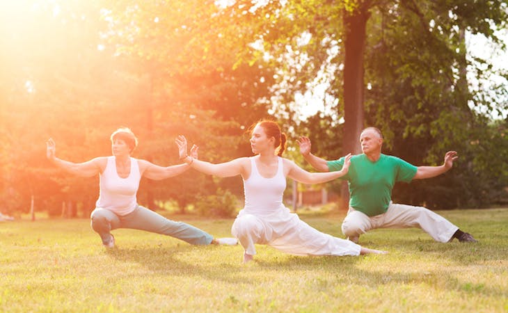 three people practicing tai chi outside