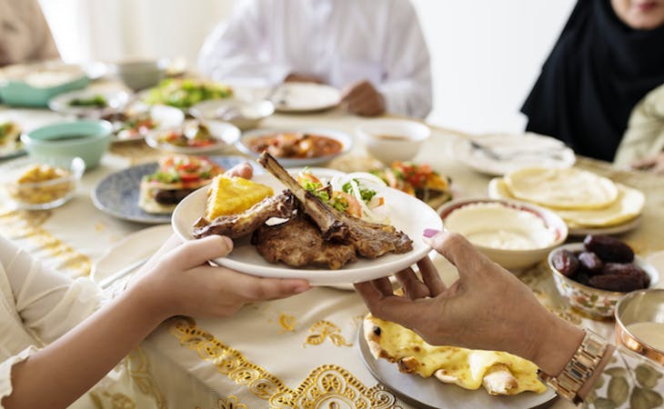 Family passing a plate of meat as part of ramadan feast