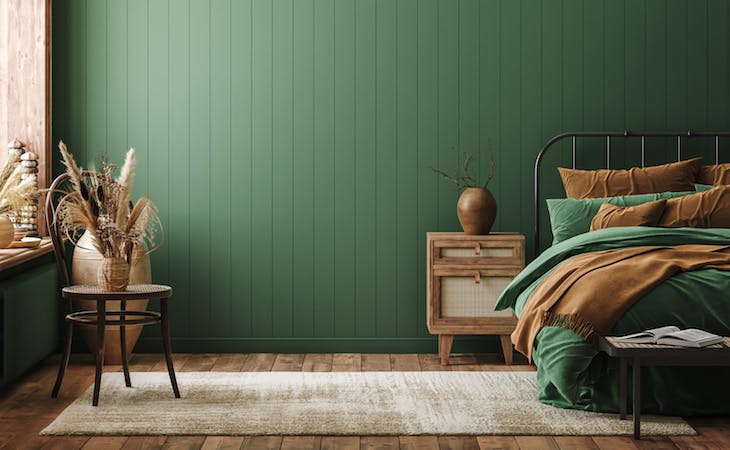 bedroom with green walls - bed with green and brown sheets on it with a nightstand next to it with wood vase on top