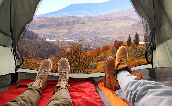 close-up of feet of two people lying down on sleeping bags inside tent