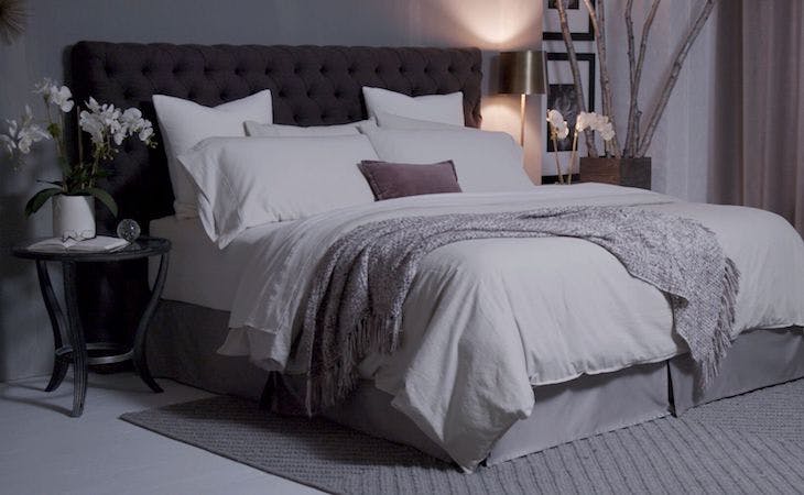 bedroom with a saatva mattress that has pillows and a gray throw blanket on top if it