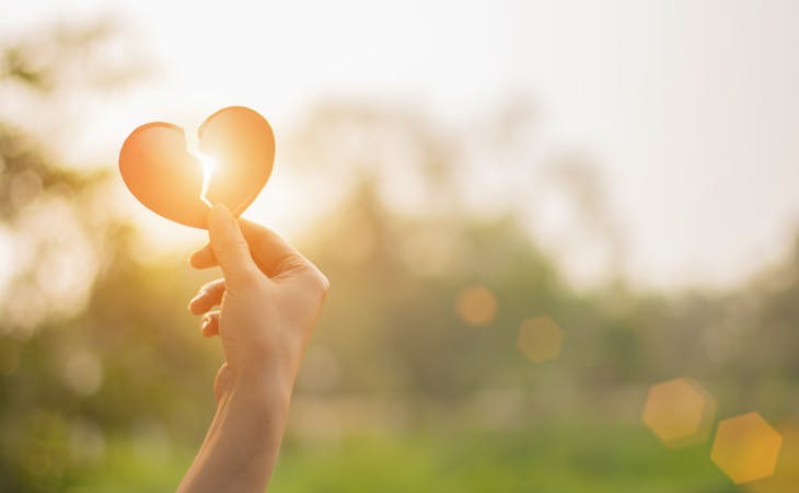 grieving person holding a broken heart