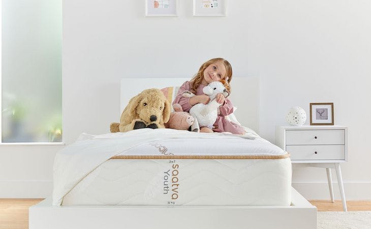 toddler sitting on top of big kid bed with stuffed animals