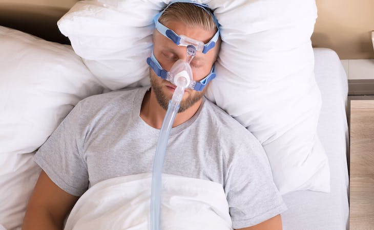 image of man with sleep apnea wearing a cpap mask in bed