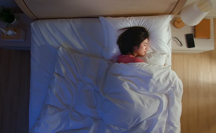 person sleeping with pillow in bed