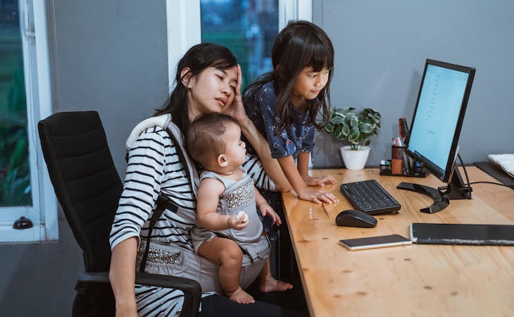 tired mom at computer with two children