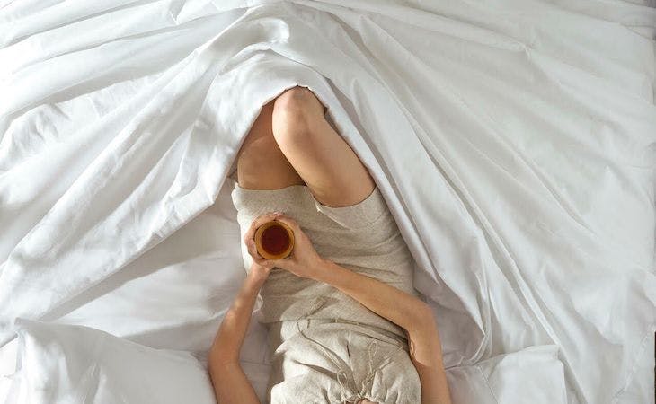 person sitting under sheets in bed