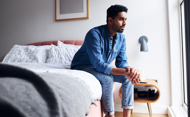 person with mental health issues sitting on edge of bed