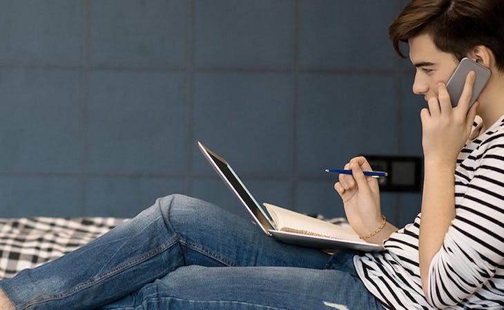 image of college student sitting on college dorm room bed