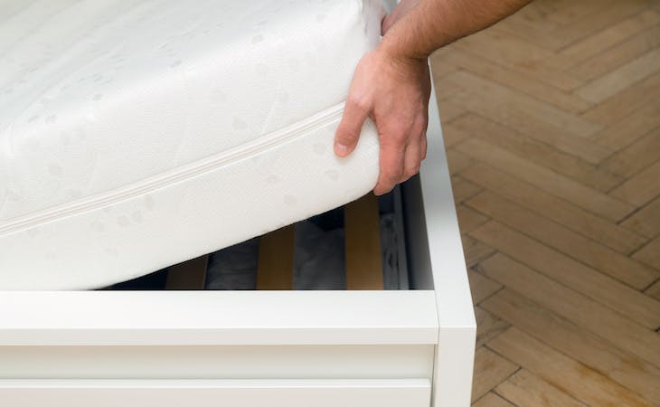 person putting mattress on top of bed frame