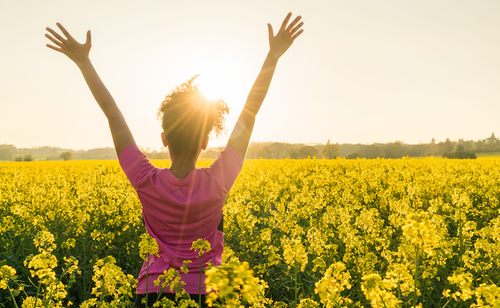 person out in sun raising arms