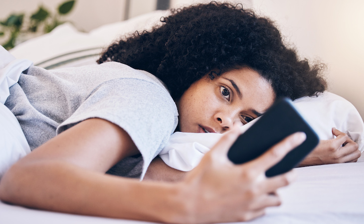 person staring at phone in bed