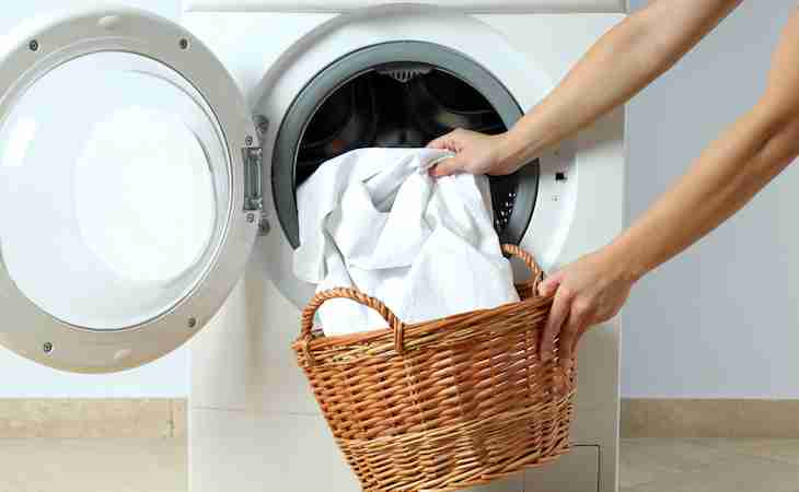 person taking white sheets out of washing machine