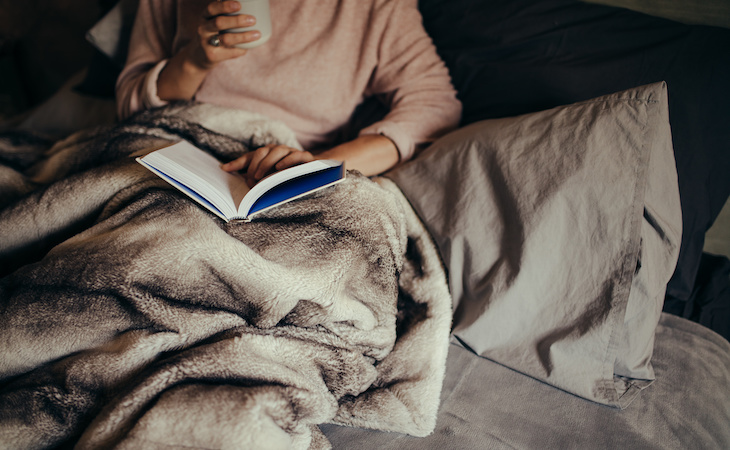 person staying in bed with book and coffee