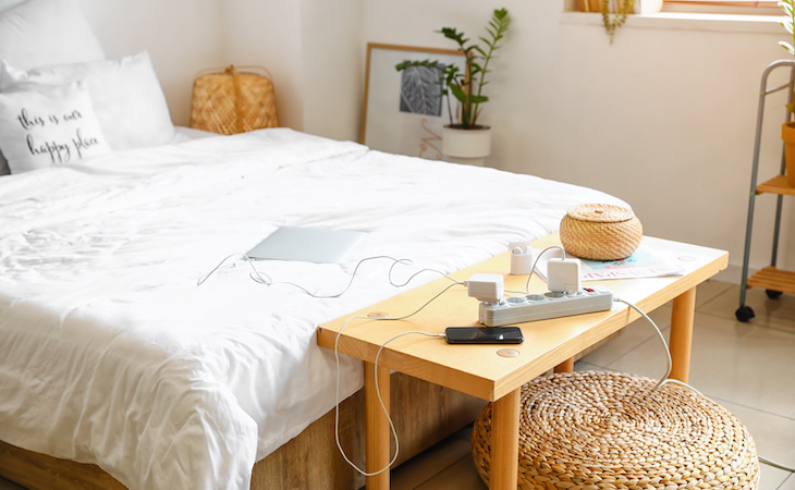 laptop and phone charging on table in bedroom