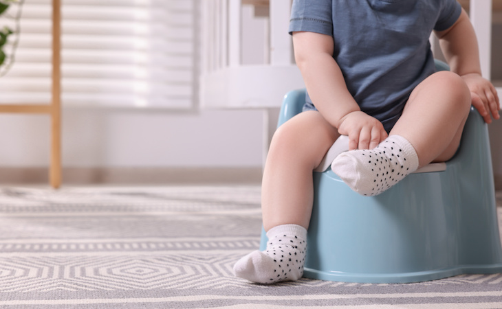 child sitting on plastic baby potty to help potty training