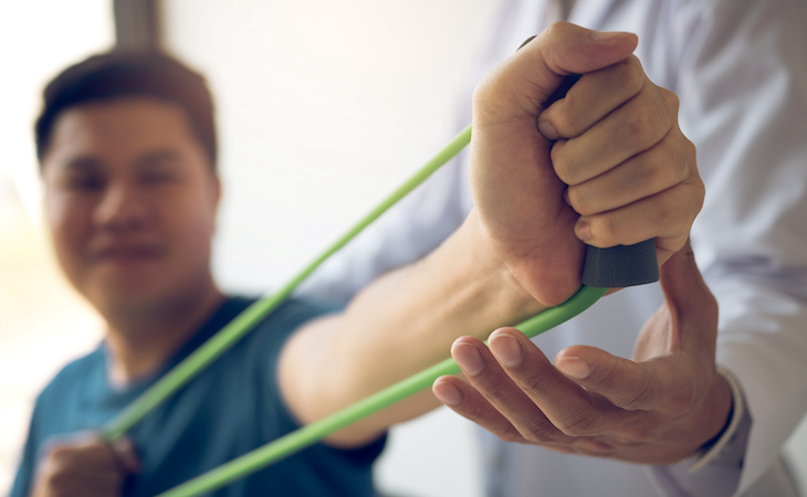 person doing stretching exercise with flexible exercise band at physical therapist