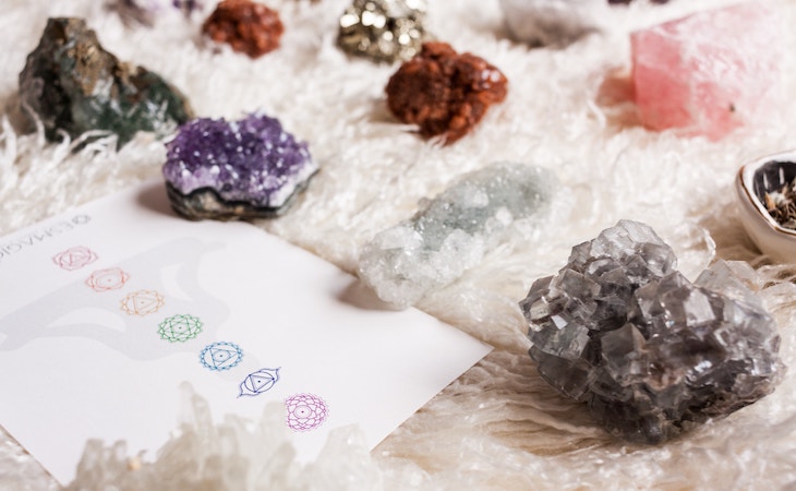 piles of crystals with a piece of paper that has the seven charka symbols on it