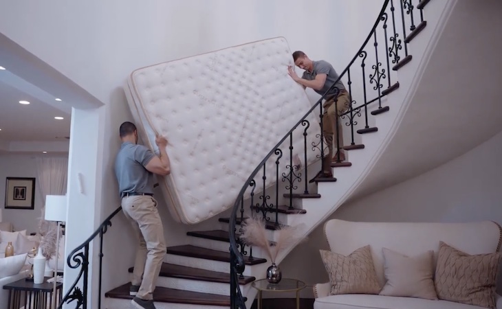 mattress delivery people bringing mattress up stairs