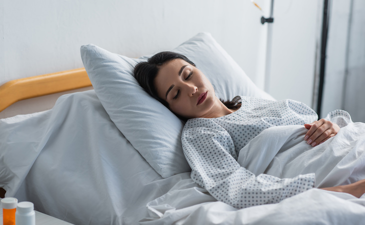 person sleeping in hospital bed after breast augmentation surgery