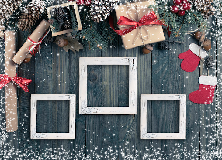 Christmas background with photo frame, spruce, gift box, Santa Claus boots and scroll in vintage style on wooden shabby boards. Top view