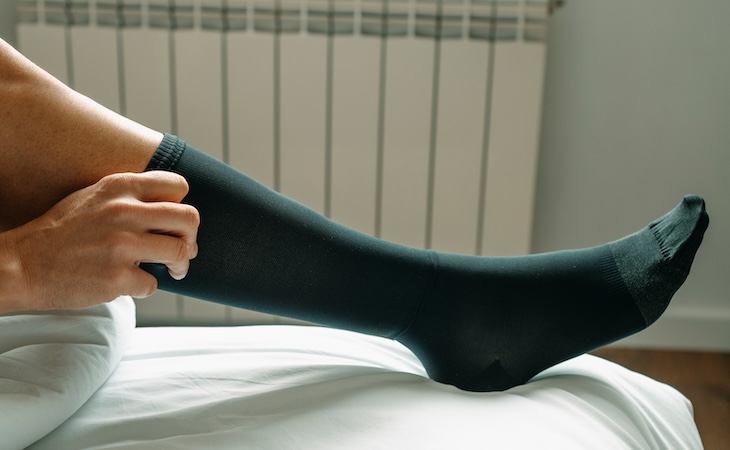 Person putting on black compression socks