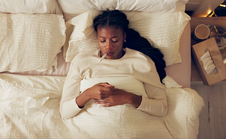 Woman resting in bed, feeling unwell.