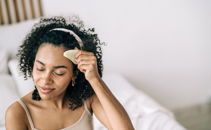 Woman using gua sha tool at night