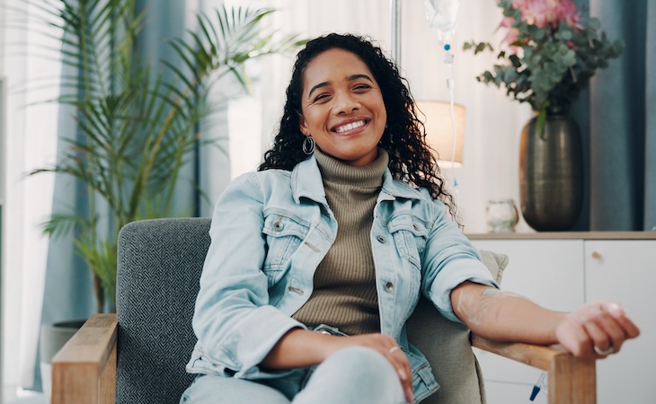 Smiling woman in cozy setting getting an IV drip