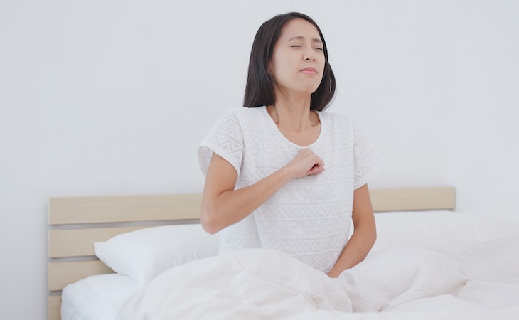 Woman experiencing chest discomfort in bed
