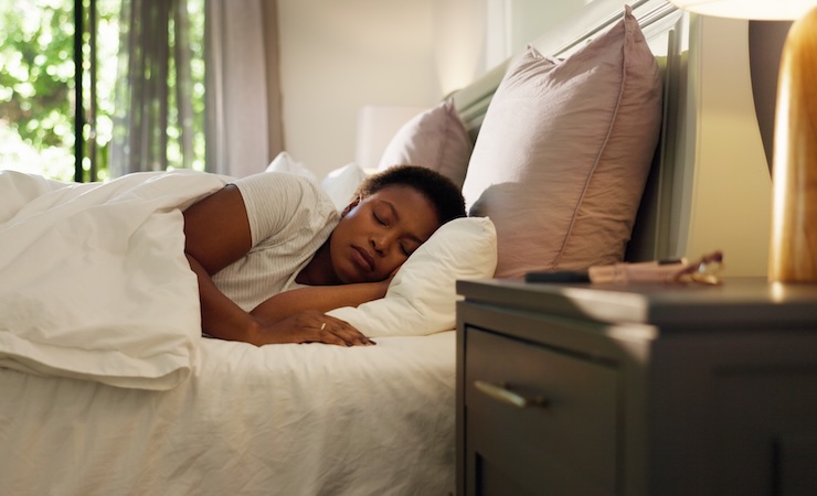 Home, tired and black woman with sleeping in bed for resting, dreaming and comfortable on pillow. Exhausted, person and asleep in bedroom for lazy weekend, relax or recovery from fatigue in apartment