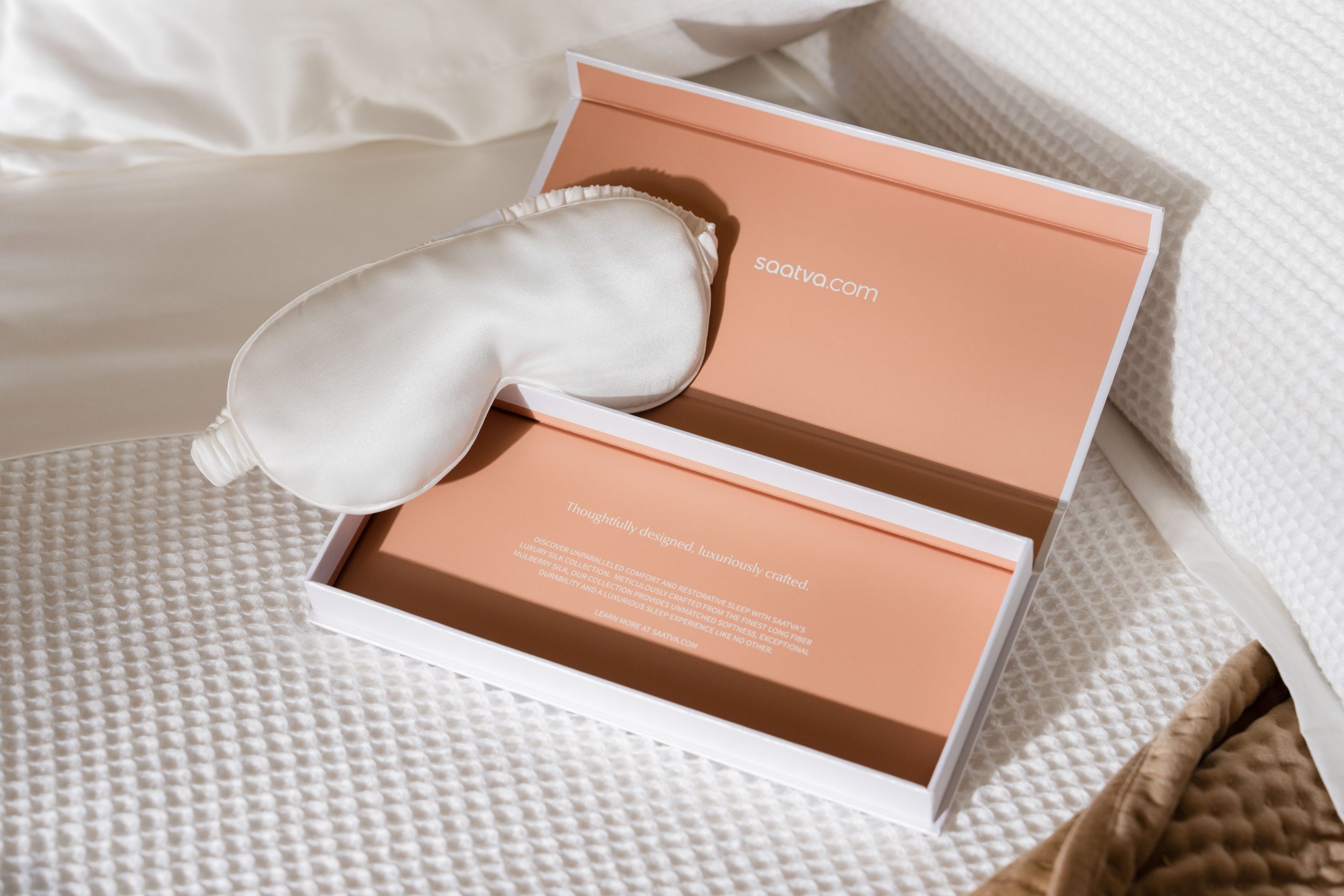Saatva's Weighted Eye Mask in white on Saatva's Waffle Knit Duvet Cover and Velvet Pickstitch Quilt.