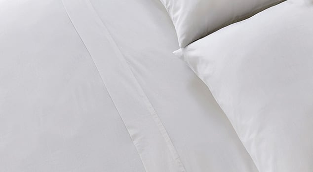 A made bed with Saatva sheets.