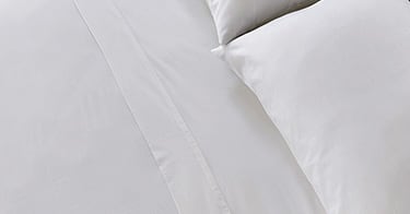 A made bed with Saatva sheets.
