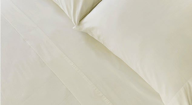 A made bed with Saatva sheets.