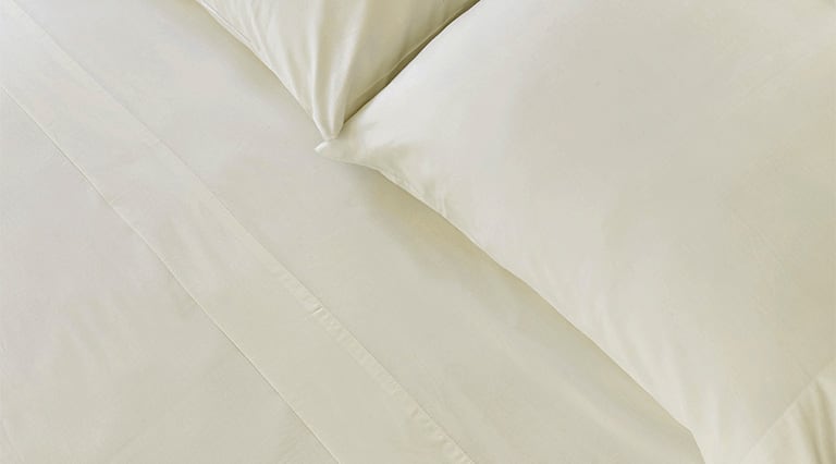 A made bed with Saatva sheets.