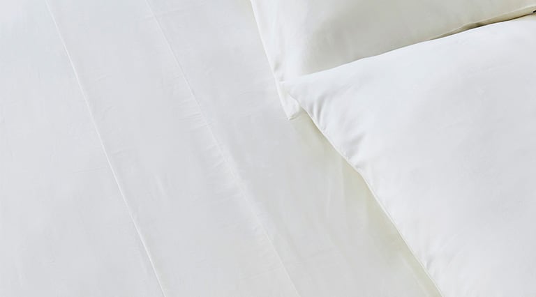 A made bed with Saatva sheets.