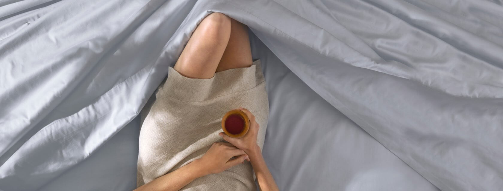 Woman lying comfortably in Saatva sheets.