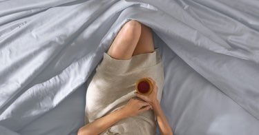 Woman lying comfortably in Saatva sheets.