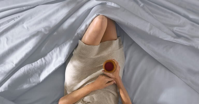 Woman lying comfortably in Saatva sheets.